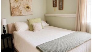 Une chambre à coucher avec un lit, des oreillers, une table de chevet et des œuvres d’art murales.
