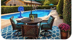 Un espace aménagé au bord de la piscine, avec une table ronde et des chaises, un panier de basketball et un grand parasol.