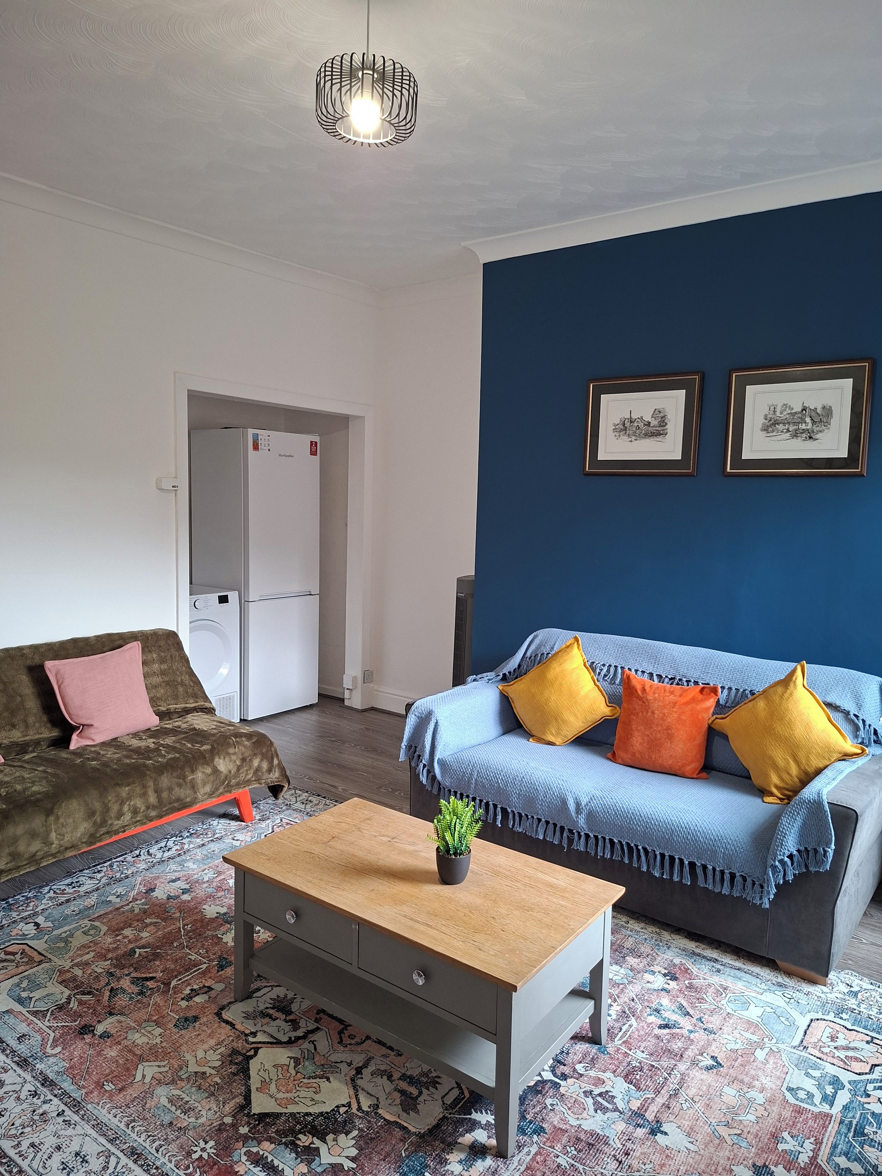 A living room with a sofa, a coffee table, a rug, and two framed pictures on the wall.