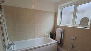 Un baño moderno con una bañera independiente, un box de ducha de vidrio y una ventana con vista a través de vidrio esmerilado.