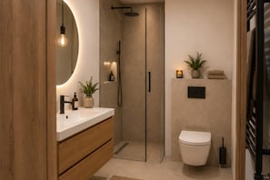 A modern bathroom with a wooden vanity, a round mirror, a toilet, and a shower enclosure.
