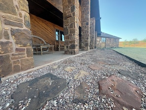 A stone building with a wooden deck and a gravel pathway.