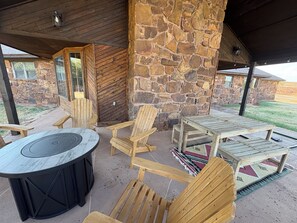 Ein Patio im Freien mit Steinwand, Holzstühlen, einem Tisch und einer Feuerstelle.
