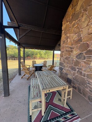 An outdoor patio with a stone wall, wooden furniture, and a patterned rug. - 3600 sq. ft. Ranch Home on acreage - Sleeps 12 (Elk City)
