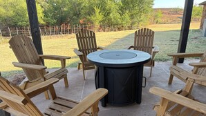Een terras met houten Adirondack-stoelen en een ronde tafel.