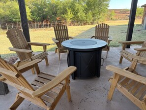 A patio area with wooden Adirondack chairs and a round table. - 3600 sq. ft. Ranch Home on acreage - Sleeps 12 (Elk City)