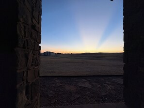 A stone wall with a view of a flat landscape and a building in the distance.