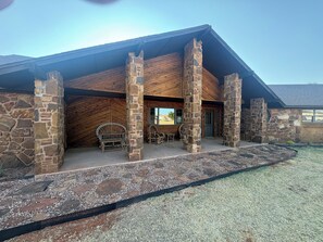 A stone building with a covered patio area, stone pillars, and a wooden ceiling.
