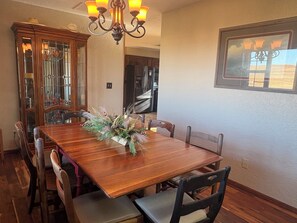 A dining room with a wooden table, chairs, a chandelier, and a decorative centerpiece.
