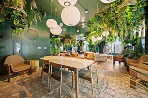 A room with a round table, chairs, sofas, hanging plants, and a large window. - Downtown Miami 1006| Rooftop Pool Hot Tub & Gym (Miami)