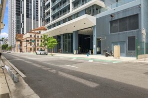 A modern building with a covered entrance, a street with a crosswalk, and a parked scooter. - Downtown Miami 1006| Rooftop Pool Hot Tub & Gym (Miami)