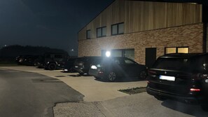 Ein Parkplatz mit mehreren Autos vor einem Gebäude mit Ziegelaußenwand und Flachdach.