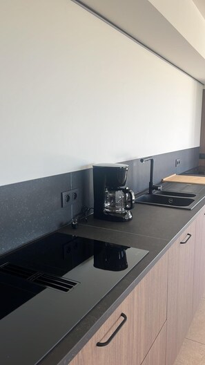 Eine moderne Küche mit schwarzem Arbeitsplatz, einer Kaffeemaschine und einem Spülbecken.