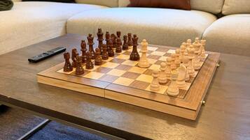 A chessboard on a wooden coffee table in a living room with a sofa and cushions in the background.