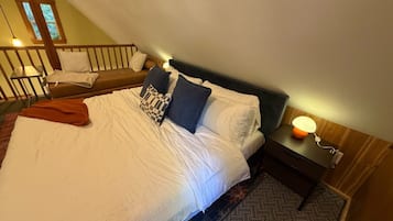 Ein ordentlich gemachtes Bett mit weißen Leinen und einer braunen Tagesdecke, ein Nachttisch mit einer Lampe und ein gemustertes Teppich.