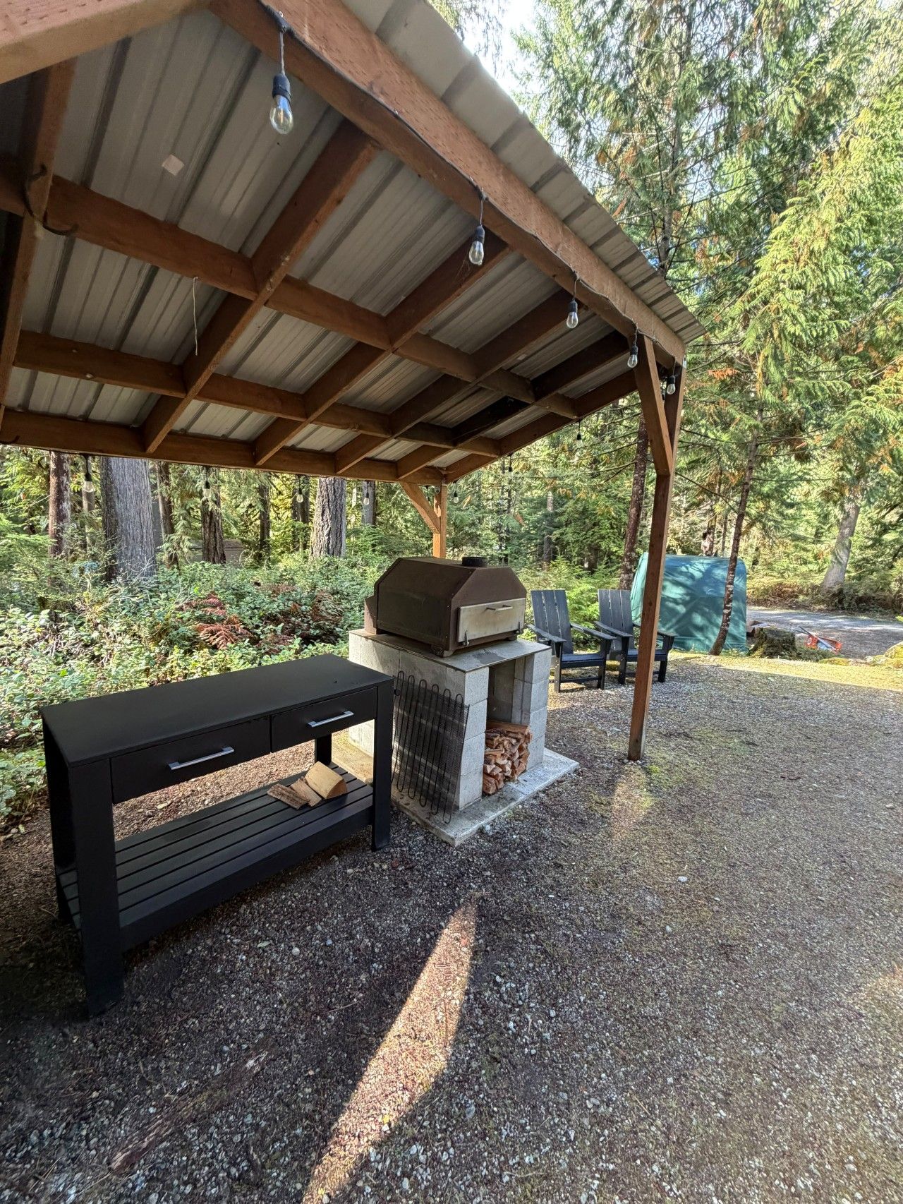 Un espacio al aire libre techado con una parrilla, un banco y una mesa.