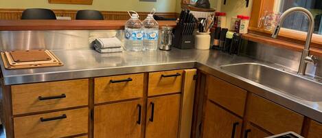 A kitchen with a central island, stainless steel appliances, wooden cabinets, and a window with a view.