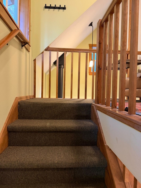 A staircase with wooden railings and carpeted steps leading to an upper floor.