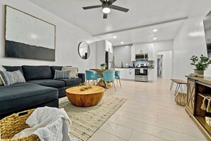 Een moderne woonkamer met een bank, salontafel en een eethoek met stoelen.