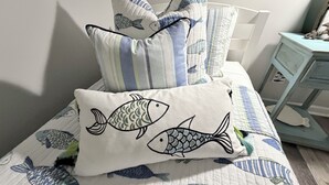 A bed with a quilted bedspread featuring fish designs, a pillow with fish embroidery, and striped pillows. - Cozy & Convenient 2-bedroom Cottage in Foley (Foley)