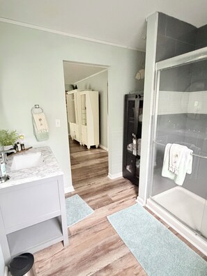 A bathroom with a shower, a sink, and a vanity. There is a hallway leading to a bedroom with a wardrobe. - Cozy & Convenient 2-bedroom Cottage in Foley (Foley)