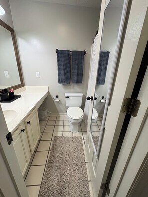 Ein Badezimmer mit Toilette, Waschbecken, Spiegel und zwei Handtüchern, die an der Wand hängen.