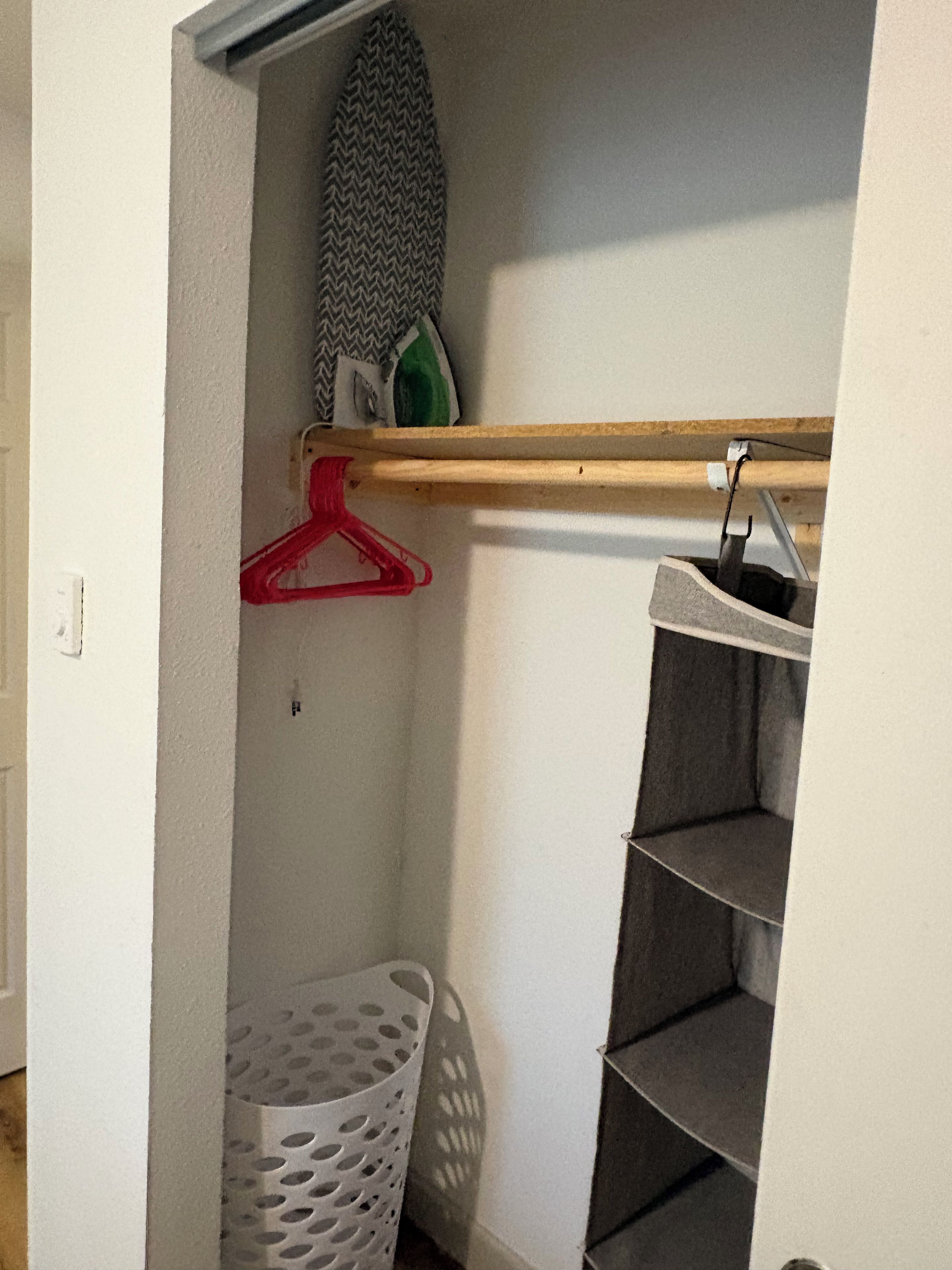 Ett förråd med hyllor, en klädstång och en tvättkorg.