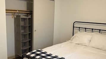 Une chambre à coucher comprenant un lit, un ventilateur de plafond, une armoire et une étagère.