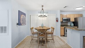 A kitchen with wooden cabinets, a microwave, and a refrigerator. - Cape Cod Retreat 601-Pool & Playground-Sleeps 8 (Panama City Beach)