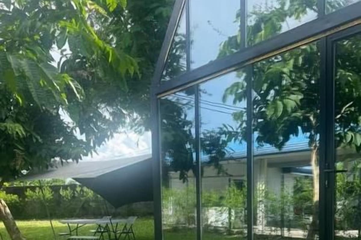 Eine Glaskonstruktion mit Steinunterbau, umgeben von Gras und Bäumen.