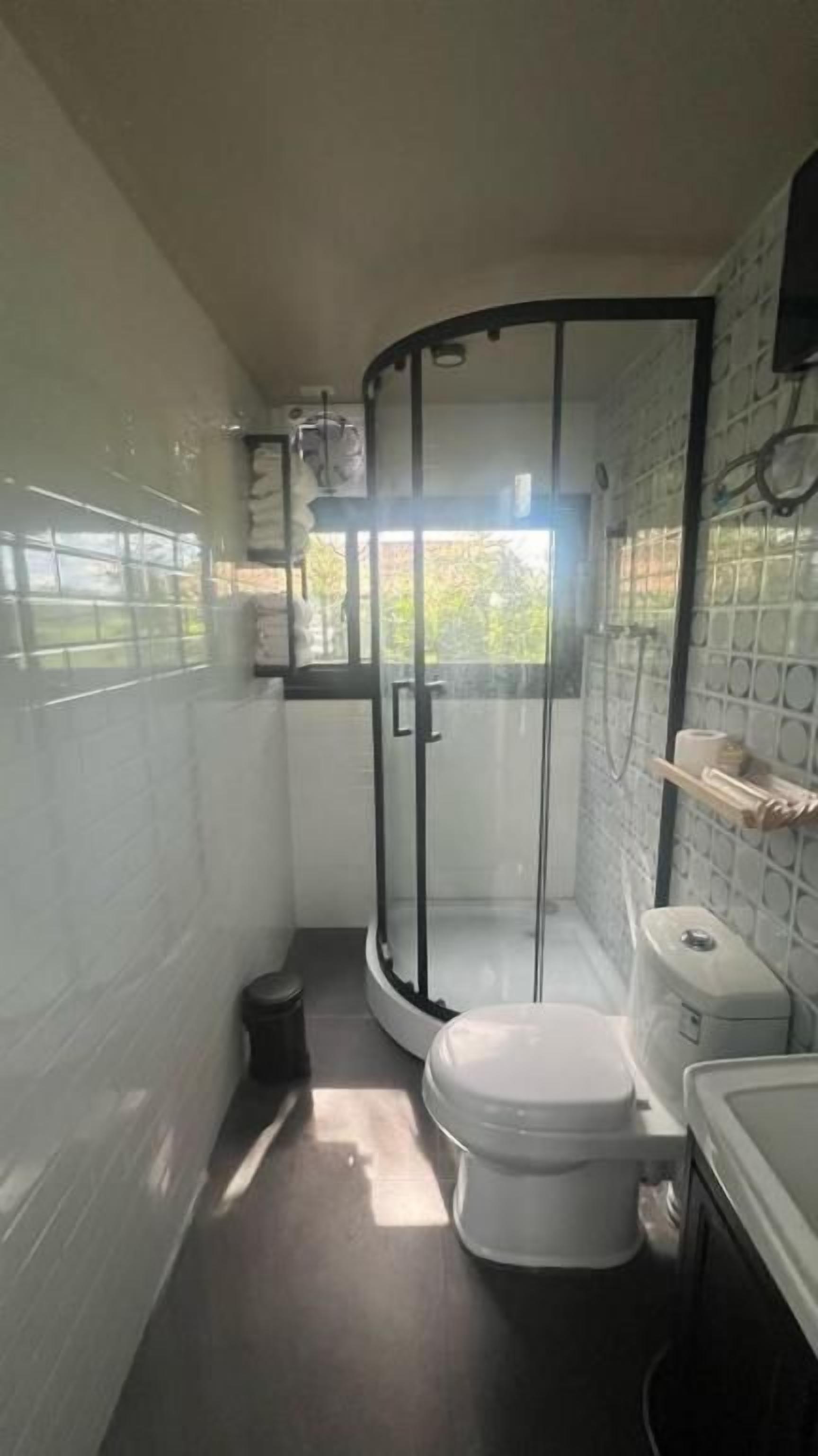 Un baño pequeño con inodoro, cabina de ducha y lavamanos.