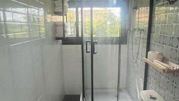Un baño pequeño con inodoro, cabina de ducha y lavamanos.
