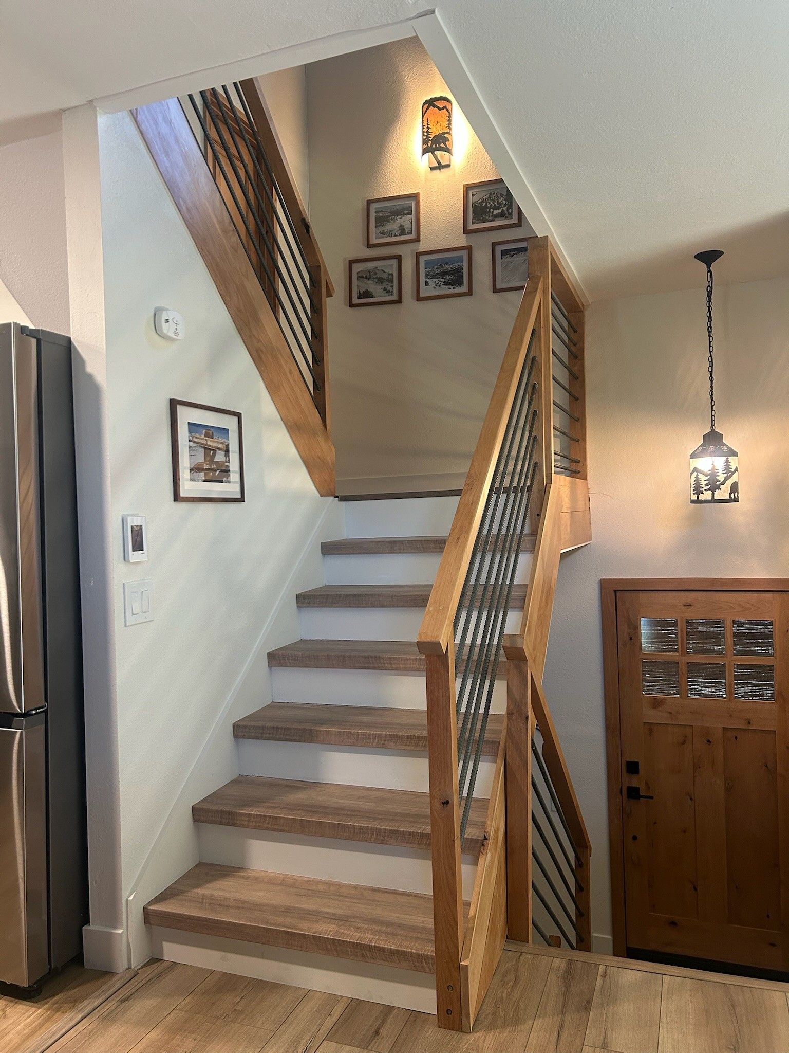 A wooden staircase with a metal railing, a refrigerator, and a door with a window panel.