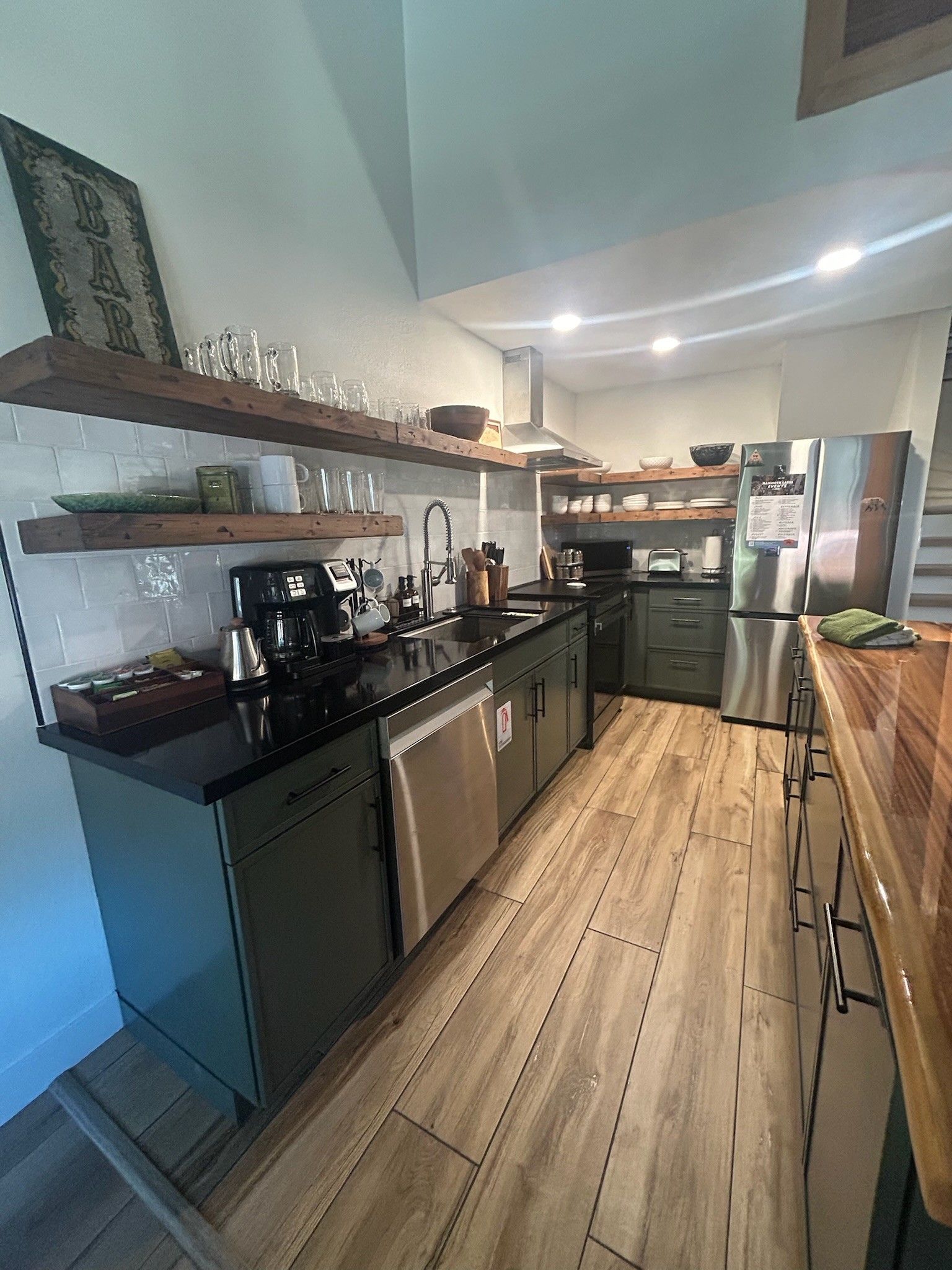 Cozinha moderna com eletrodomésticos de aço inoxidável, piso de madeira e forno embutido.