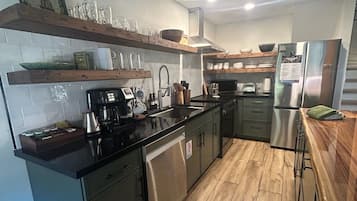 Cozinha moderna com eletrodomésticos de aço inoxidável, piso de madeira e forno embutido.