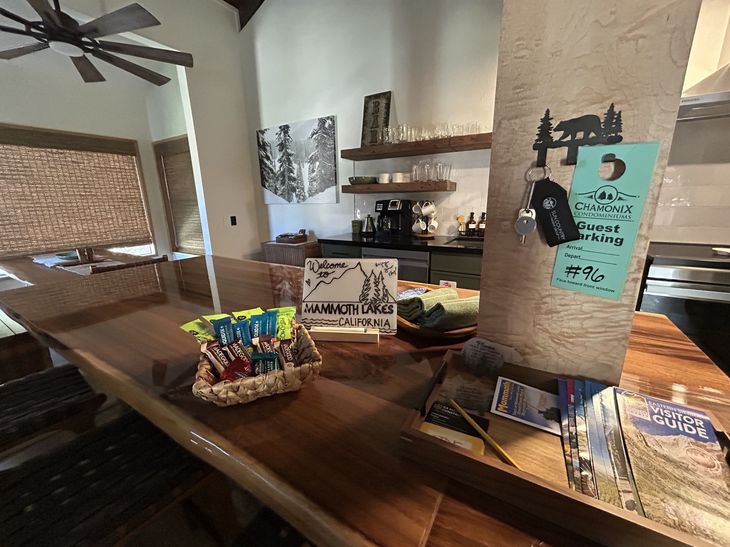 A reception area with a wooden counter, a welcome sign for Mammoth Lakes, California, and a guest parking sign.