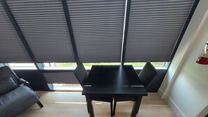 Un intérieur moderne avec une table et des chaises noires, un plancher en bois et une vue dégagée grâce à de grandes fenêtres.