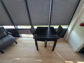 A modern interior with a black table and chairs, wooden flooring, and a view through large windows. - Modern Deluxe Loft 103 (Peachland)