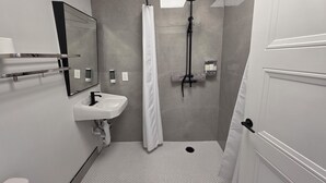 Une salle de bain équipée d’une douche, d’un lavabo, de toilettes et d’un miroir.