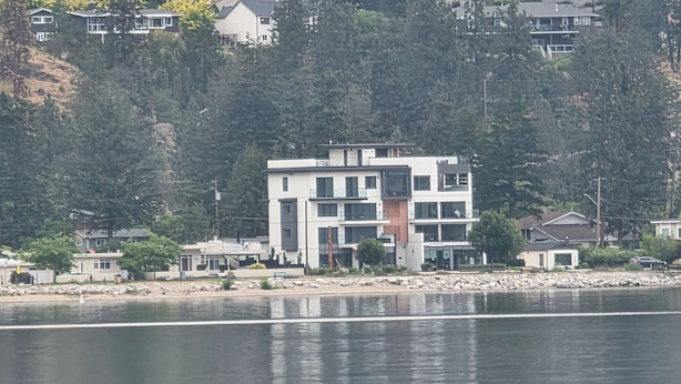 Un immeuble moderne à plusieurs étages, doté d’un toit plat, situé près d’une étendue d’eau.