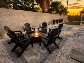 An outdoor seating area with a fire pit and chairs. - NEW 4 BR 3 BTH w/Hot Tub, Casita, Home Gym, Game Room, Arcade, 2 Mins To Airport (Las Vegas)