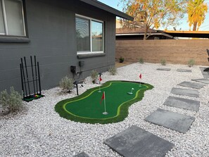 A miniature golf course with a putting green, flags, and a brick wall in the background. - NEW 4 BR 3 BTH w/Hot Tub, Casita, Home Gym, Game Room, Arcade, 2 Mins To Airport (Las Vegas)
