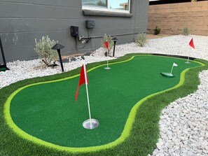 Ein Minigolfplatz mit Kunstrasen, Fahnen und einem Kiesstreifen.