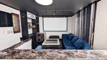 A modern living room with a marble countertop, a blue sofa, a small table, and a large window with curtains.