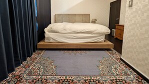 Quarto moderno com cama, mesa de cabeceira, luminária e tapete estampado.