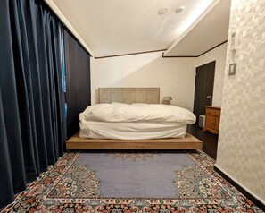 Ein modernes Schlafzimmer mit einem Bett, einem Nachttisch, einer Lampe und einem gemusterten Teppich.