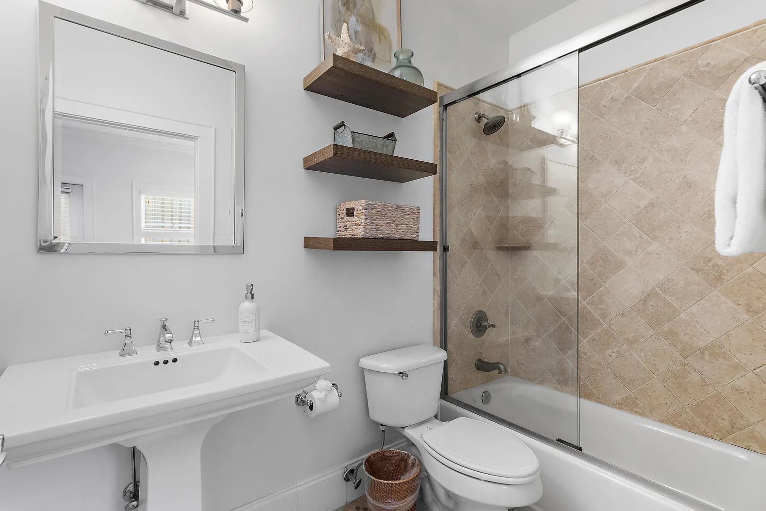 Een moderne badkamer met een douchecabine van glas, een witte wastafel en een toilet.