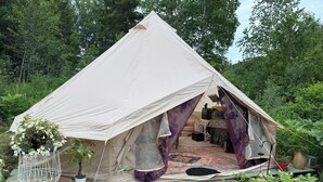 Ein Zelt mit Bett, Tisch und einer hängenden Pflanze.