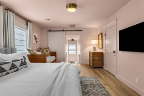Ein Schlafzimmer mit Bett, Nachttisch, Lampe und einem Fernseher an der Wand.