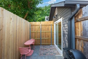 Eine Terrasse mit Tisch, Stühlen, einem Grill und einem Holzzaun.